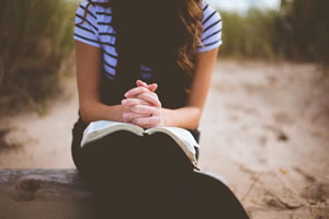Jeune femme qui prie avec bible par Ben White (unsplash.com)