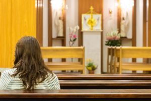 Femme en prière dans une église de Mateus Campos Felipe (unsplash.com)